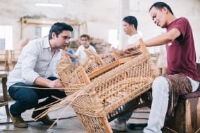 craftsman explaining his process of weaving a lounge chair while Andrew T Palecek watches
